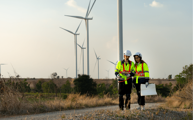 Engineers inspecting wind turbines in field